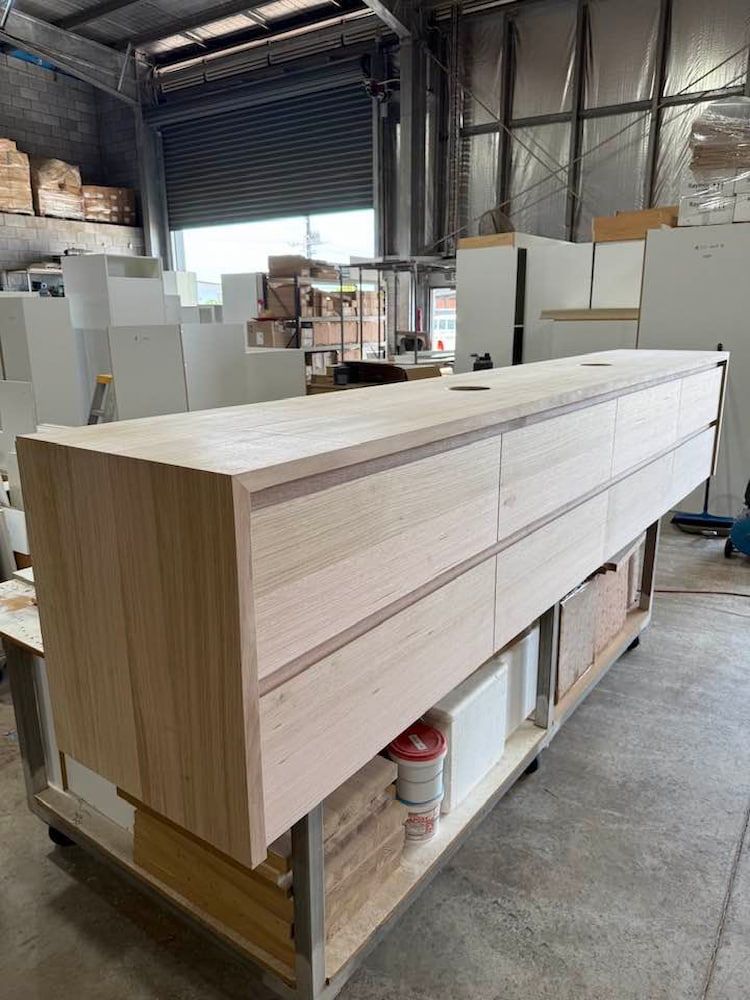 A Long Wooden Dresser is Sitting on Top of a Cart in a Warehouse — Designer Kitchens in Berrimah, NT
