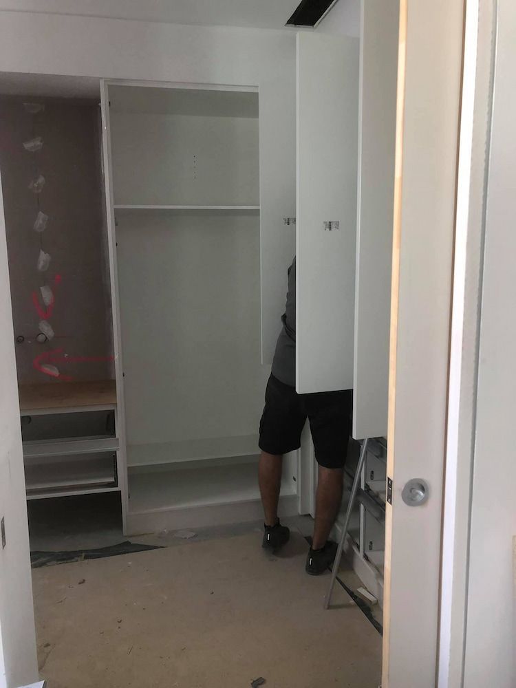 A Man is Standing in a Closet With a Ladder — Designer Kitchens in Berrimah, NT