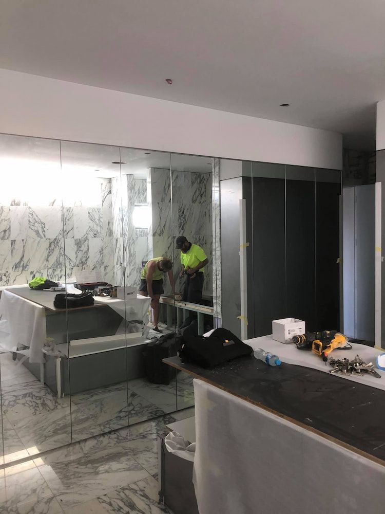A Man is Standing in a Bathroom With a Lot of Mirrors — Designer Kitchens in Berrimah, NT