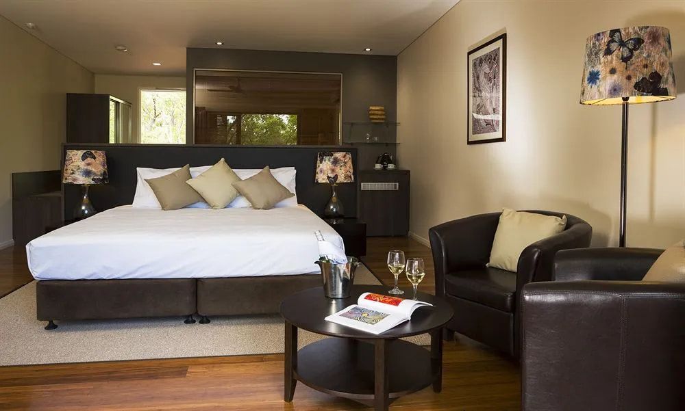 A Hotel Room With a King Size Bed and Two Chairs — Designer Kitchens in Berrimah, NT