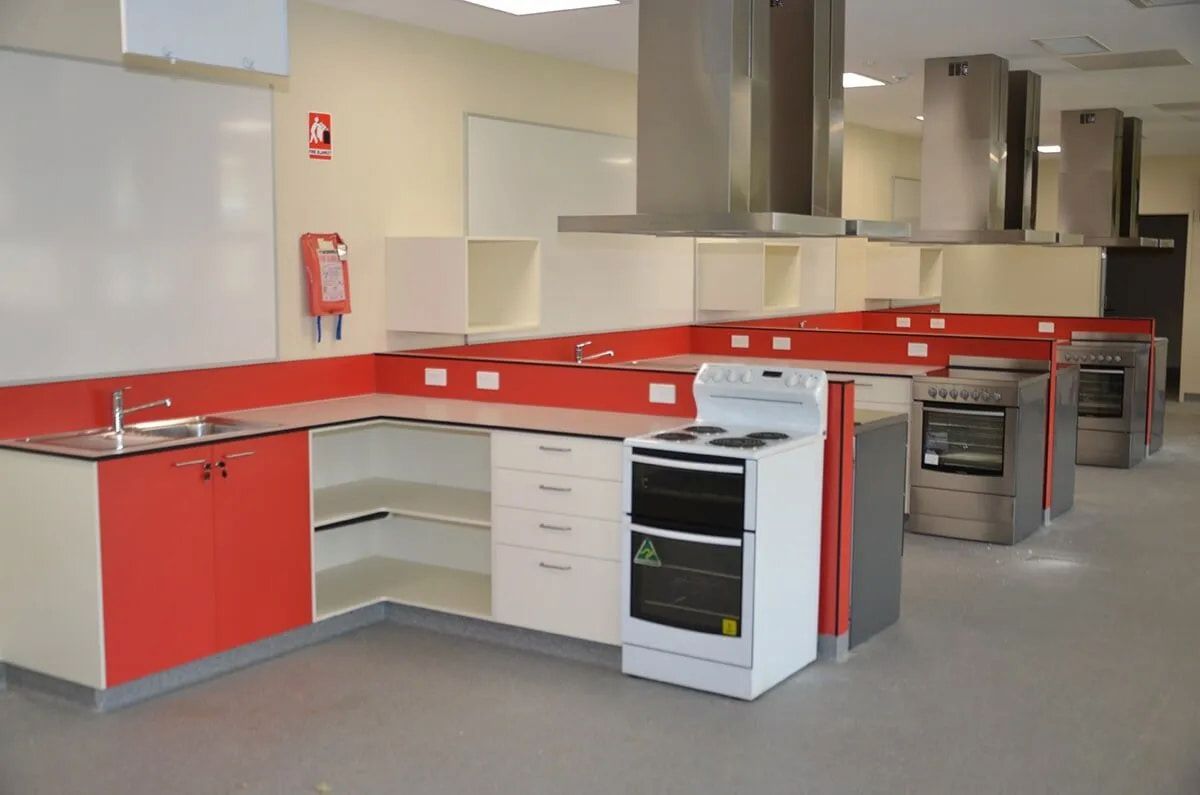 A Kitchen With Red Cabinets and White Appliances — Designer Kitchens in Berrimah, NT