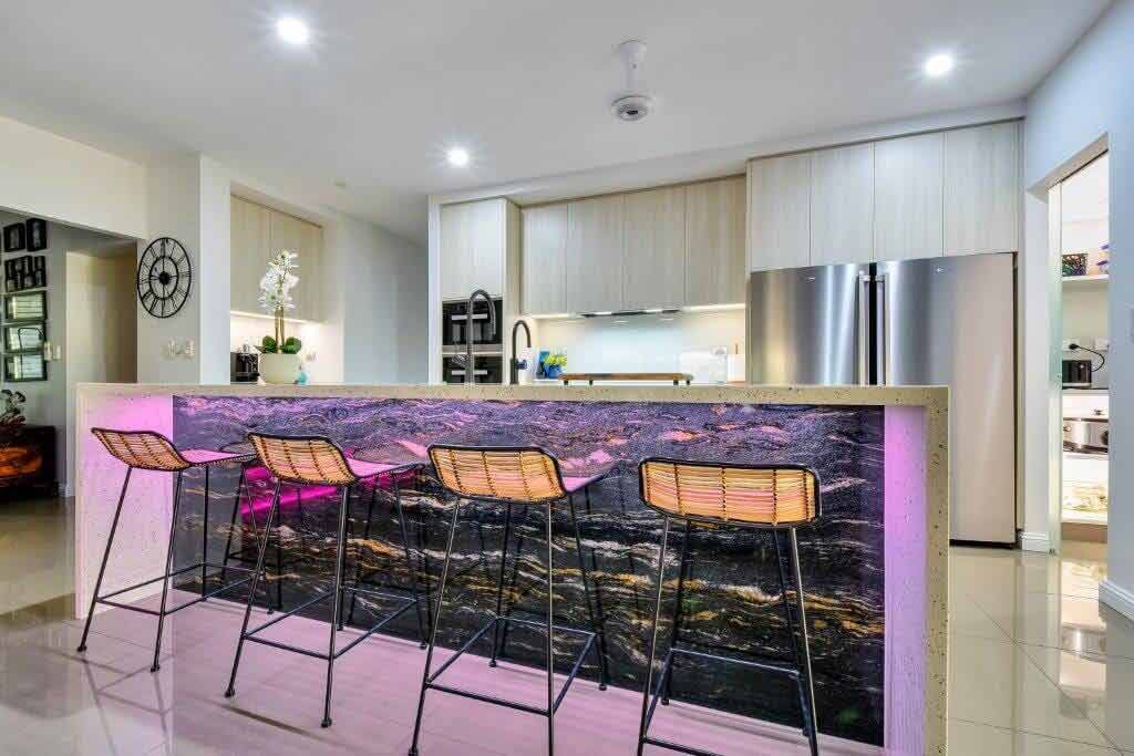 A Kitchen With a Bar and Stools and a Refrigerator — Designer Kitchens in Berrimah, NT