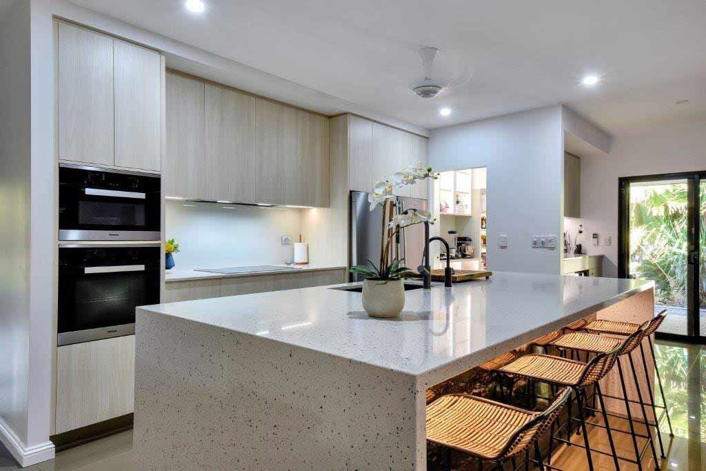 A Kitchen With a Large Island and Stools — Designer Kitchens in Berrimah, NT