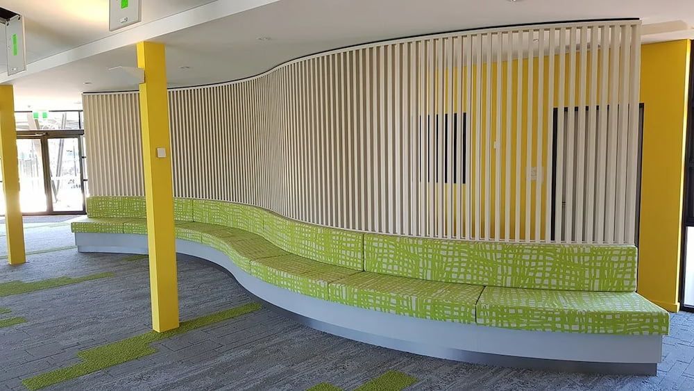 A Waiting Room With a Curved Bench and a Yellow Wall — Designer Kitchens in Berrimah, NT