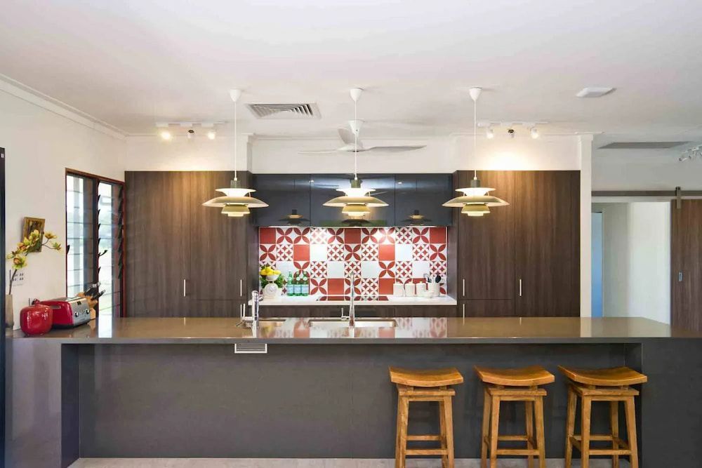 A kitchen with a large island, stools, and a sink — Designer Kitchens in Berrimah, NT
