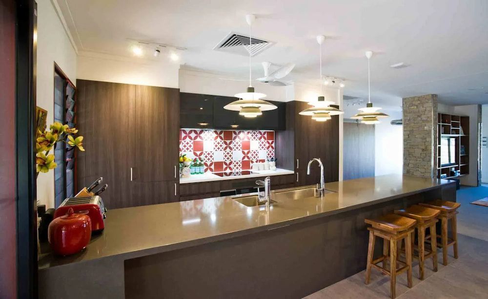 A Kitchen With a Long Counter and Stools and a Sink — Designer Kitchens in Berrimah, NT