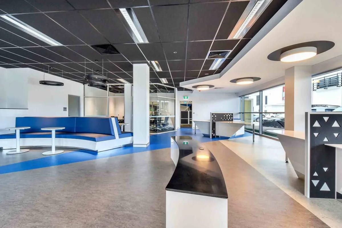 A Large Empty Room With a Blue Couch and Tables — Designer Kitchens in Berrimah, NT