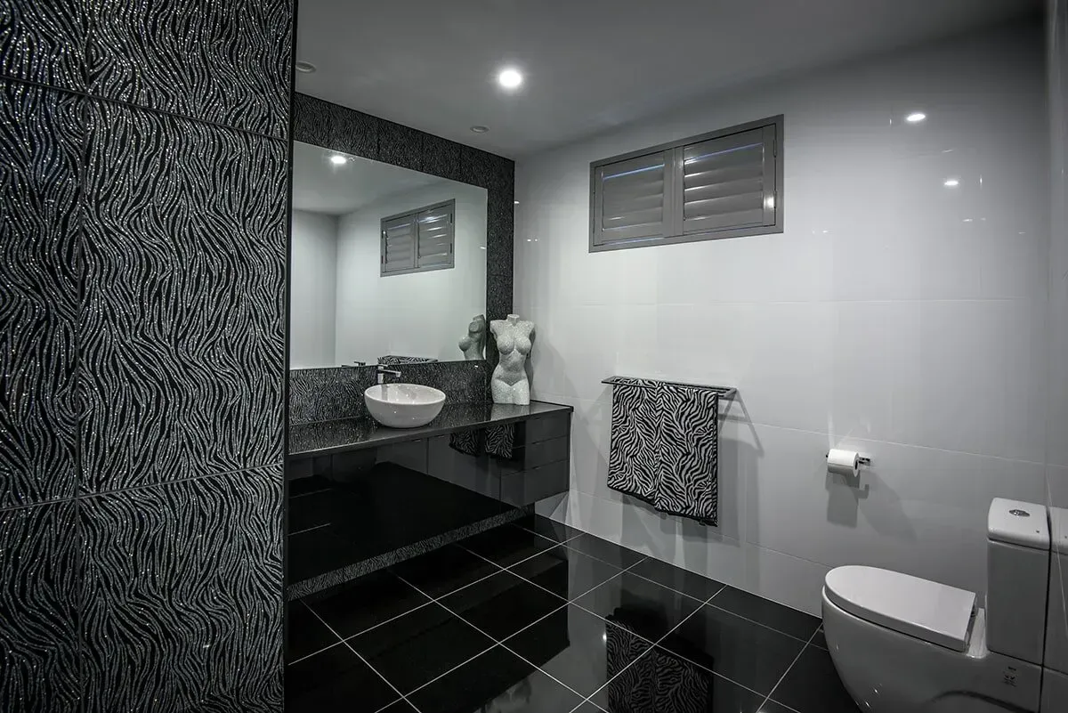 A Bathroom With a Toilet, Sink and Mirror — Designer Kitchens in Berrimah, NT