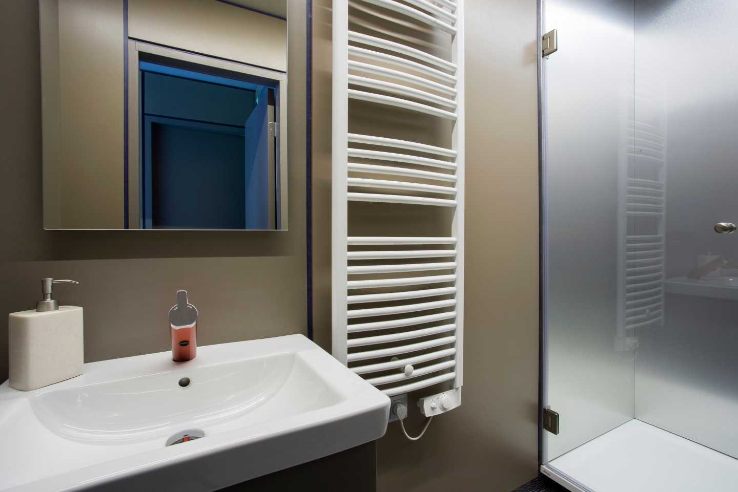 A bathroom with a sink , towel rack , mirror and shower.