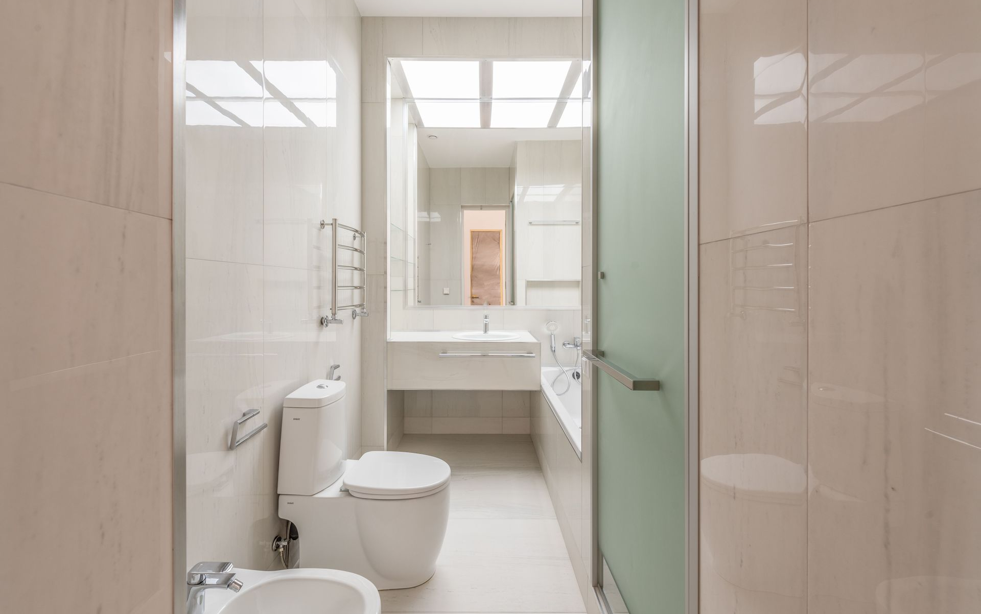 Bright bathroom with toilet, sink, large mirror, and frosted glass shower door