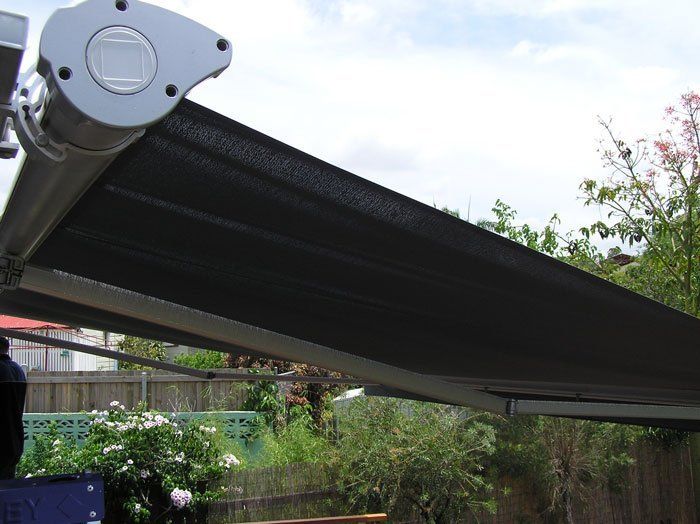 Black Awning is Hanging Over a Fence in a Backyard — Blind Outfitters in Atherton, QLD