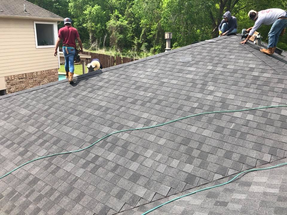 A group of men are working on the roof of a house.