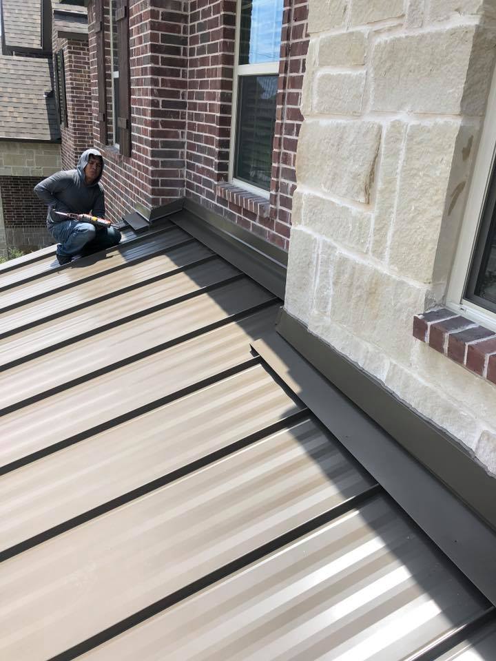 A man is kneeling on the roof of a building.