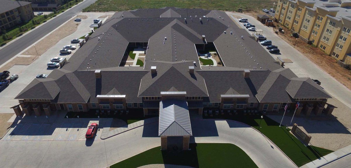 An aerial view of a large building with a red car parked in front of it