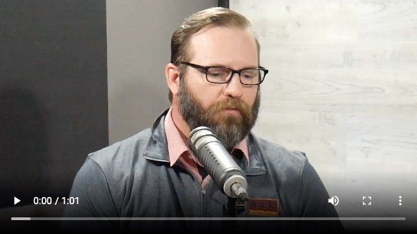 A man with a beard and glasses is speaking into a microphone