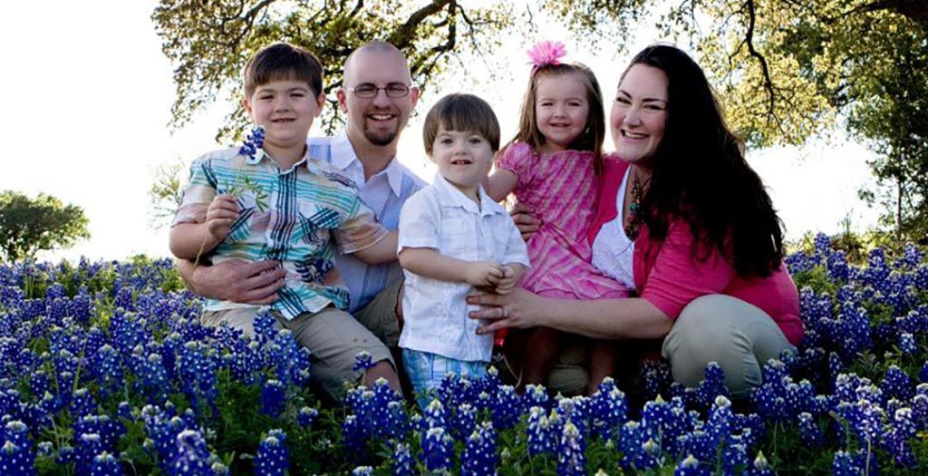 A family is posing for a picture in a field of blue flowers.
