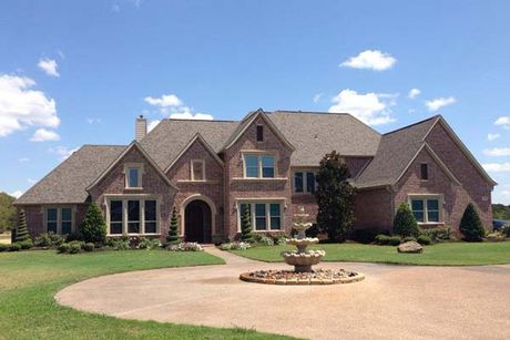 A large brick house with a fountain in front of it
