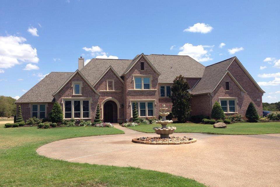 A large brick house with a fountain in front of it
