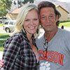 A man and a woman are posing for a picture together . the woman is wearing a plaid shirt.