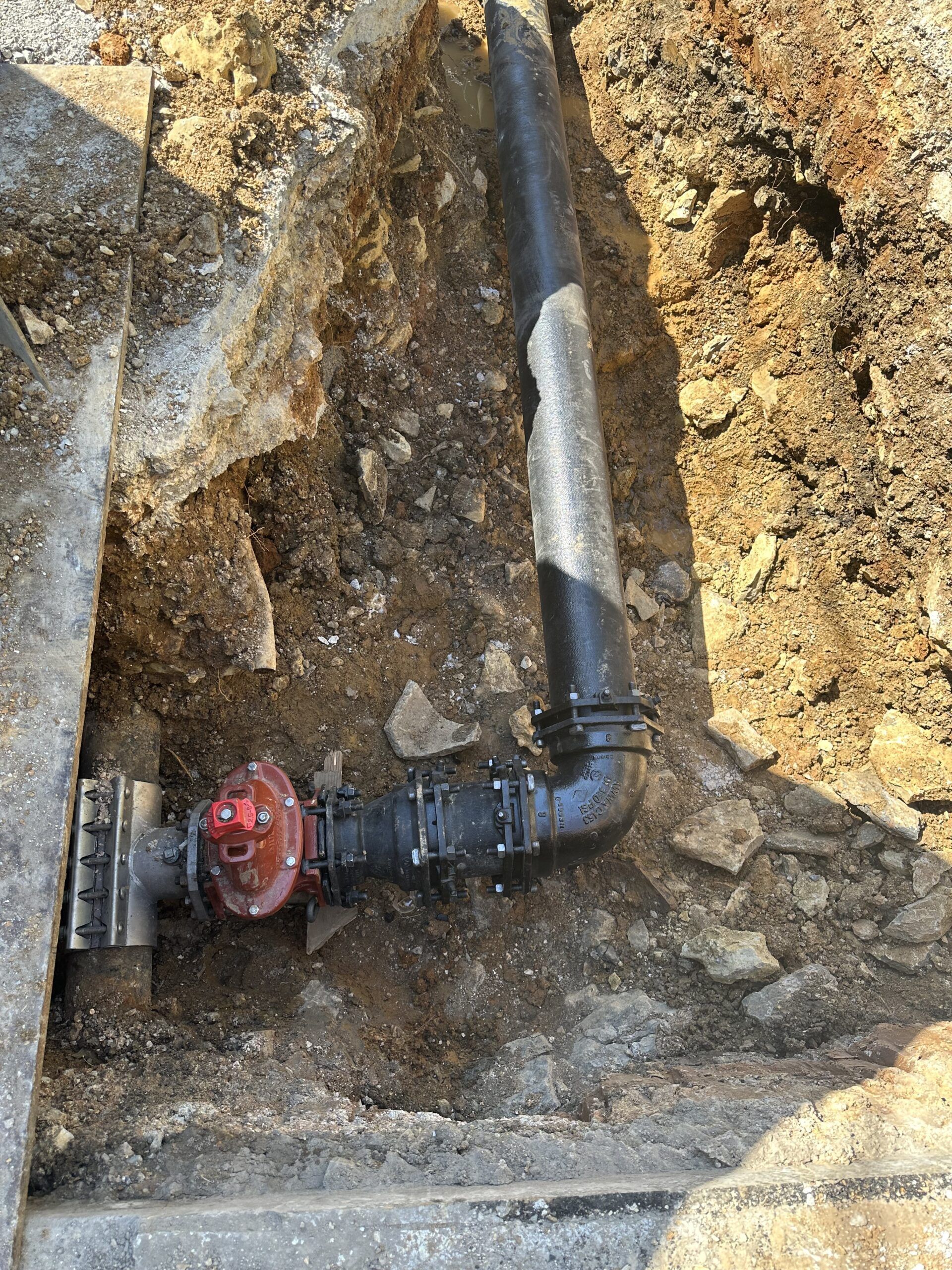 A fire hydrant is sitting in the dirt next to a pipe.