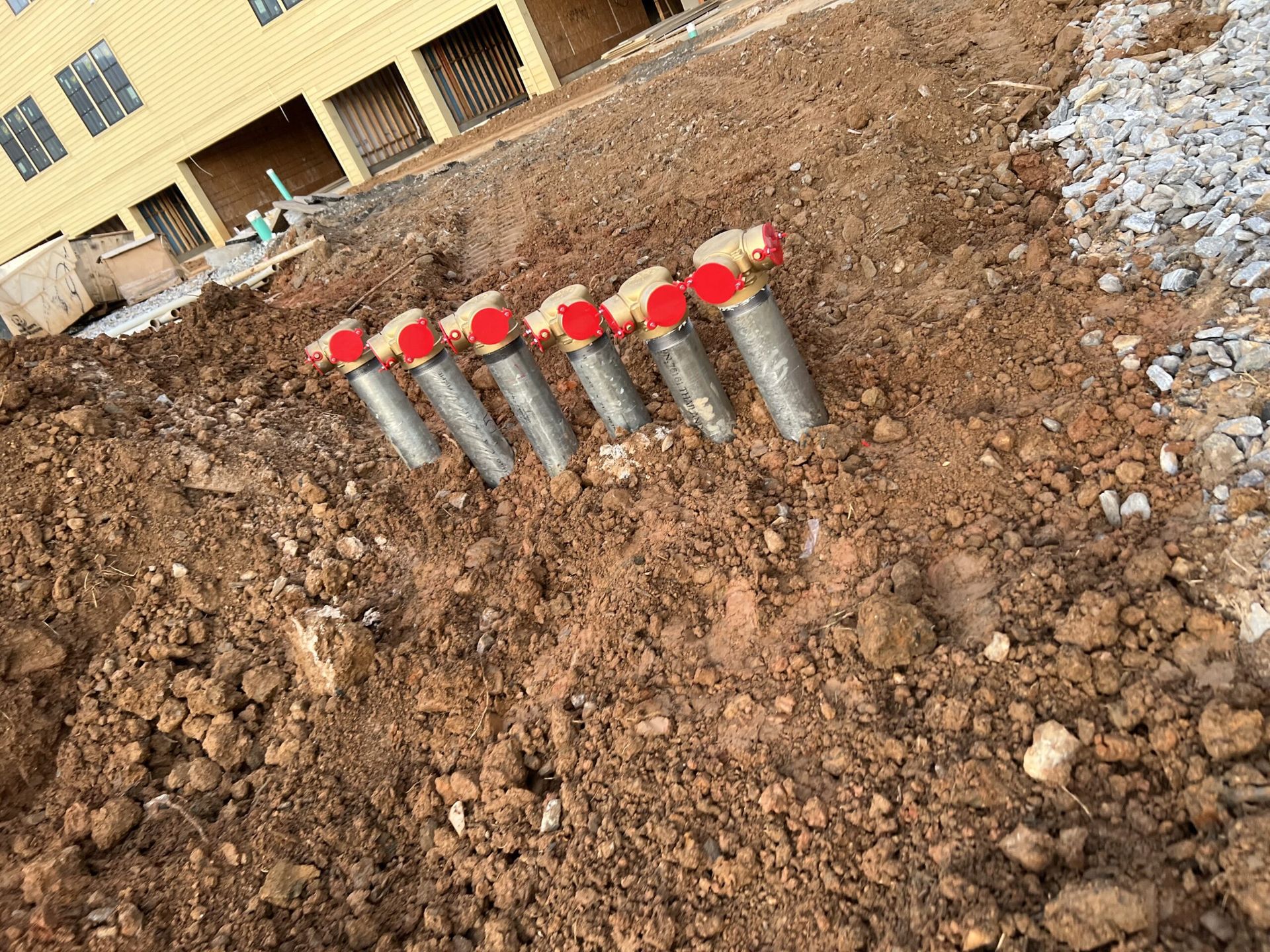 A bunch of screws are sitting in the dirt in front of a building.