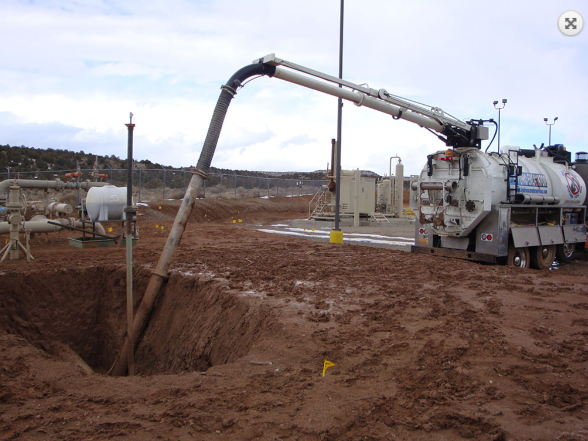 A toolbox is sitting on top of a pile of dirt next to a hole in the ground.