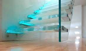 Una escalera de cristal con luces azules en los escalones de un pasillo.