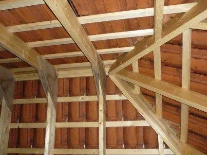 Het plafond van een gebouw met houten balken en tegels.