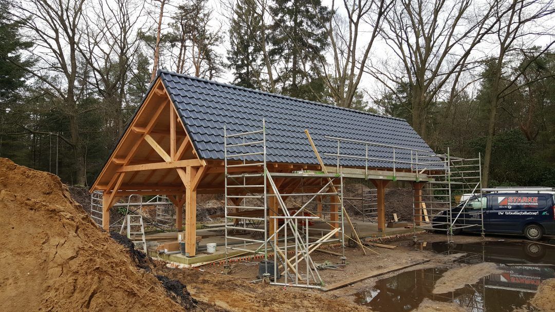 Midden in een bos wordt een houten gebouw gebouwd.