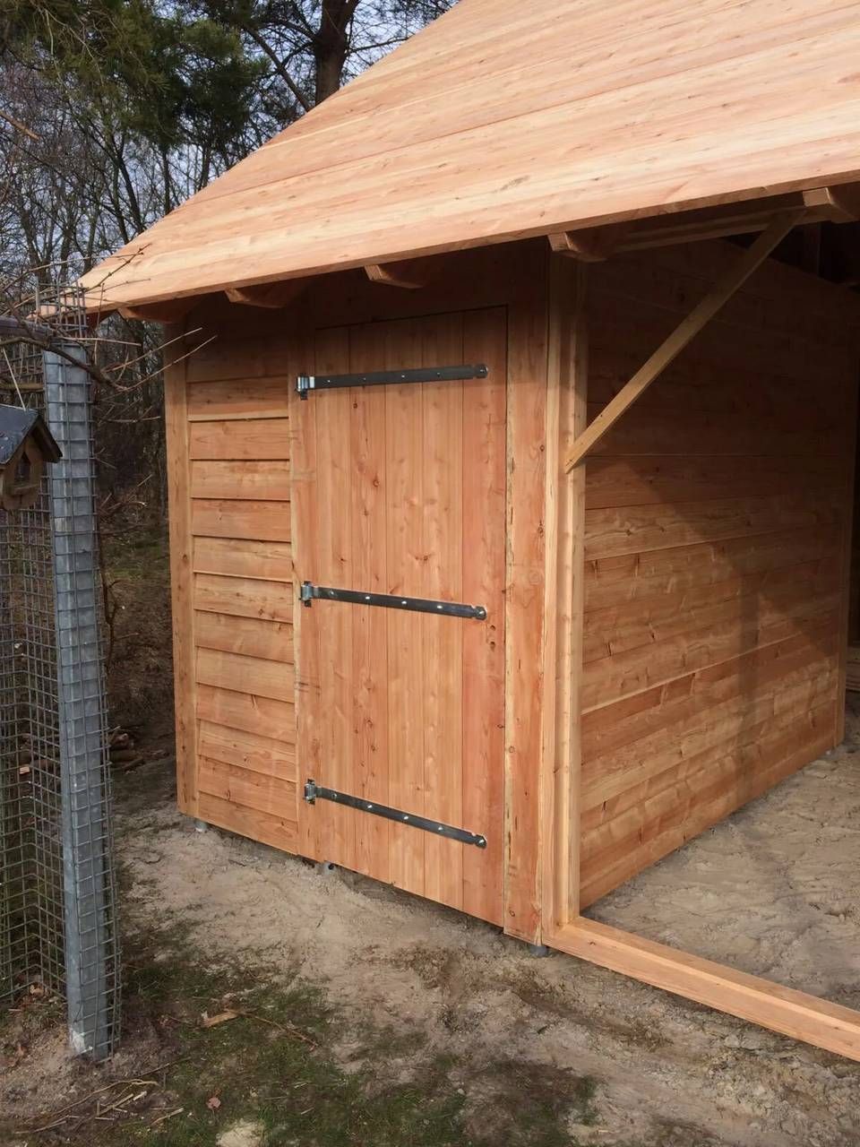 Een houten schuur met een dak en een deur