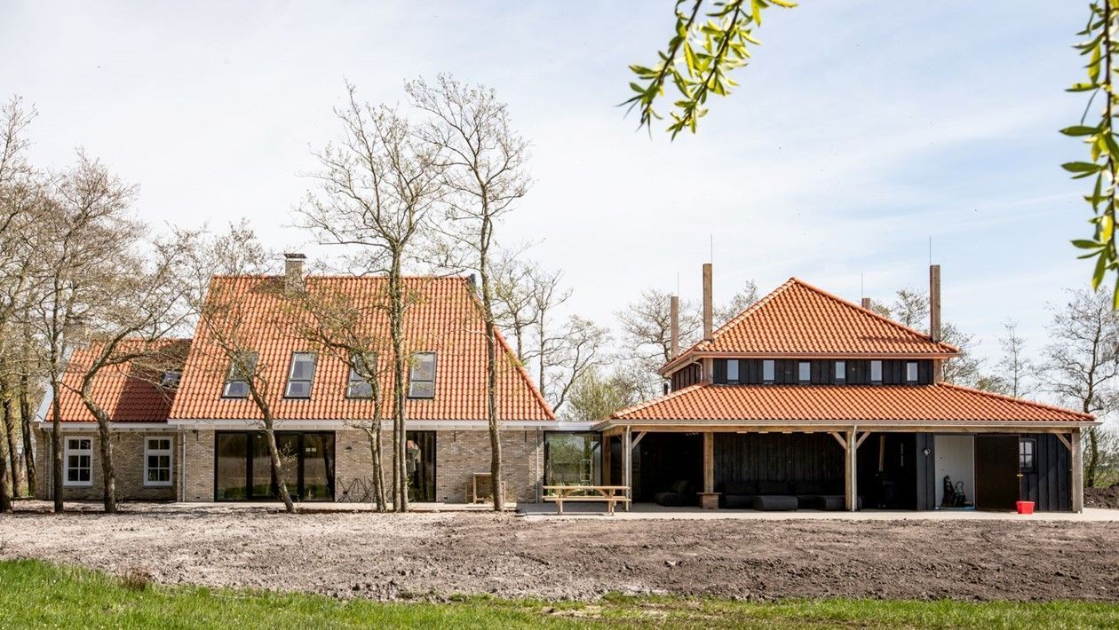 Een groot huis met een rood pannendak is omgeven door bomen.