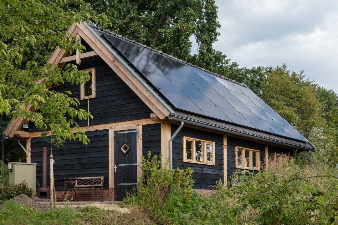 Een klein zwart huisje met zonnepanelen op het dak.