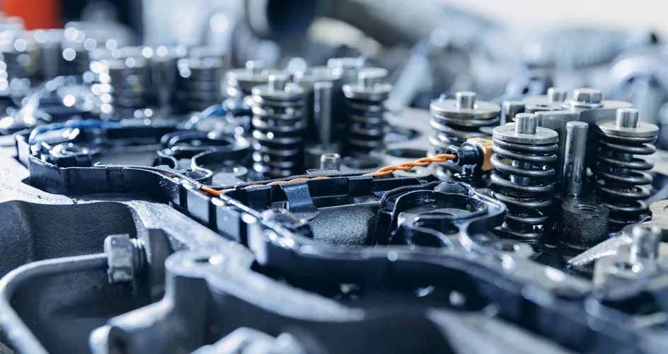 Gros plan sur une culasse de moteur à combustion interne, avec les ressorts de soupapes et les composants mécaniques visibles.