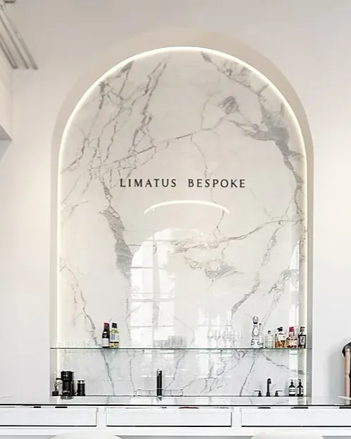 A woman is measuring a man 's arm with a tape measure at limatus bespoke in san antonio, texas.