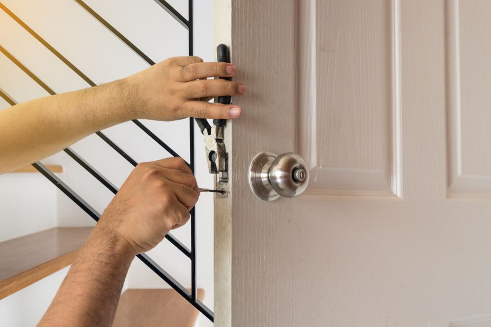 A Person Is Fixing a Door with A Screwdriver — The Lock Doctor in Morisset, NSW