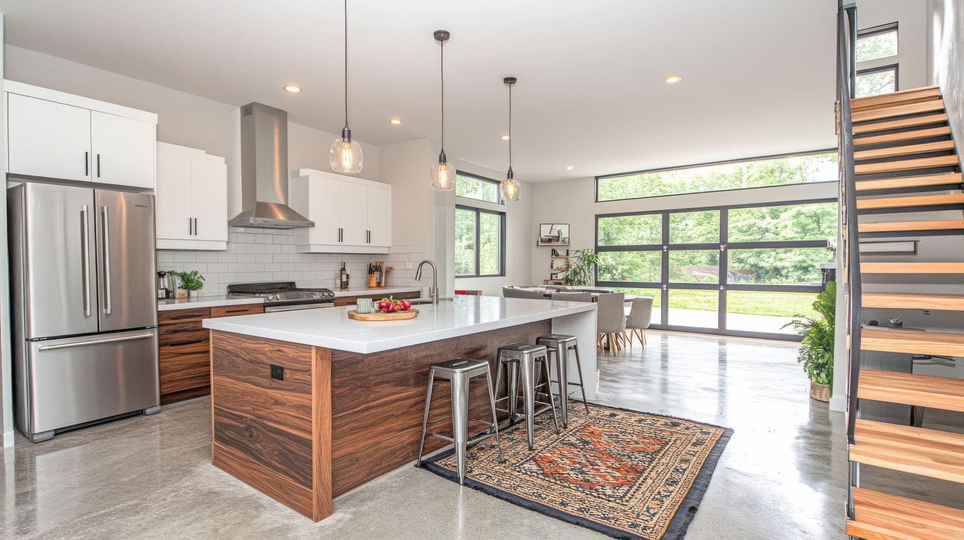 Bright modern kitchen with stainless fridge, island seating, and large windows opening to a patio