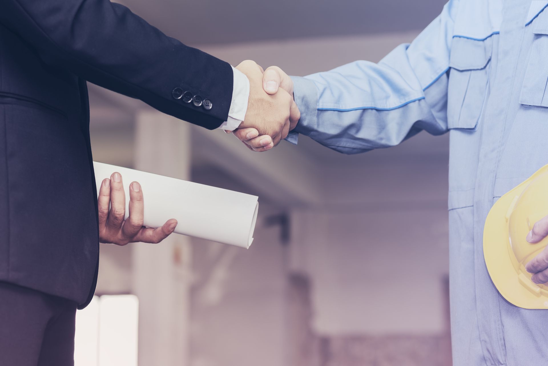 a man in a hard hat shakes hands with a man in a suit