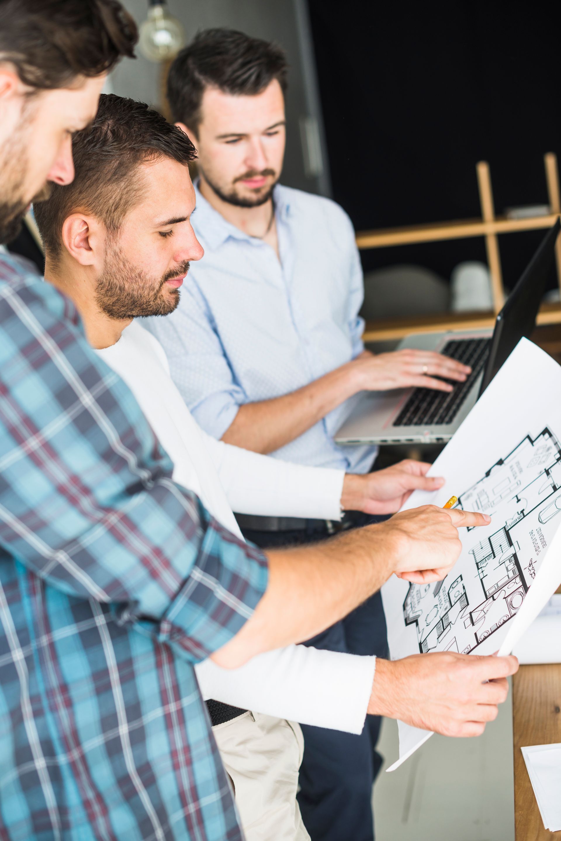 three men are looking at a floor plan of a house