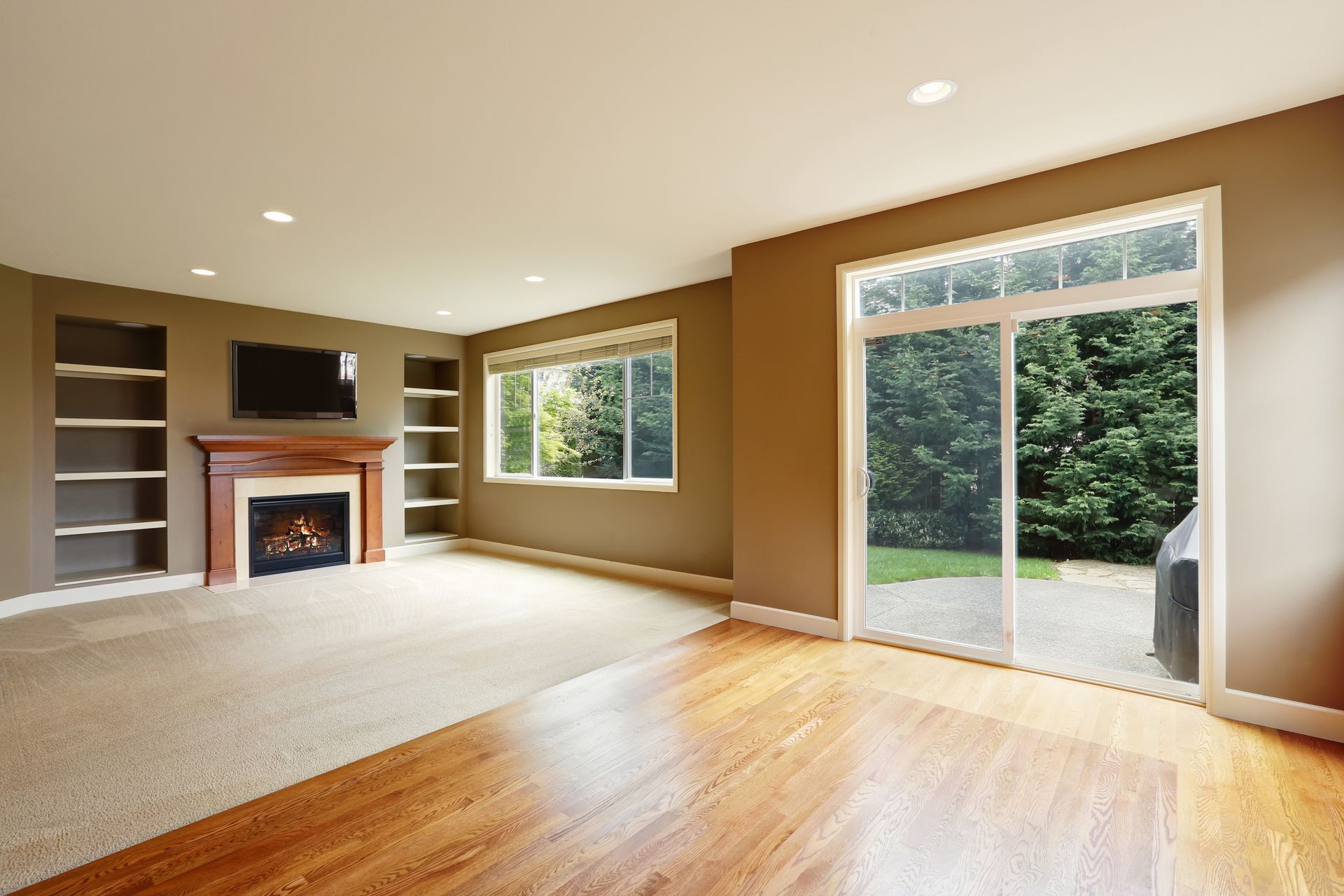 an empty living room with a fireplace and sliding glass doors
