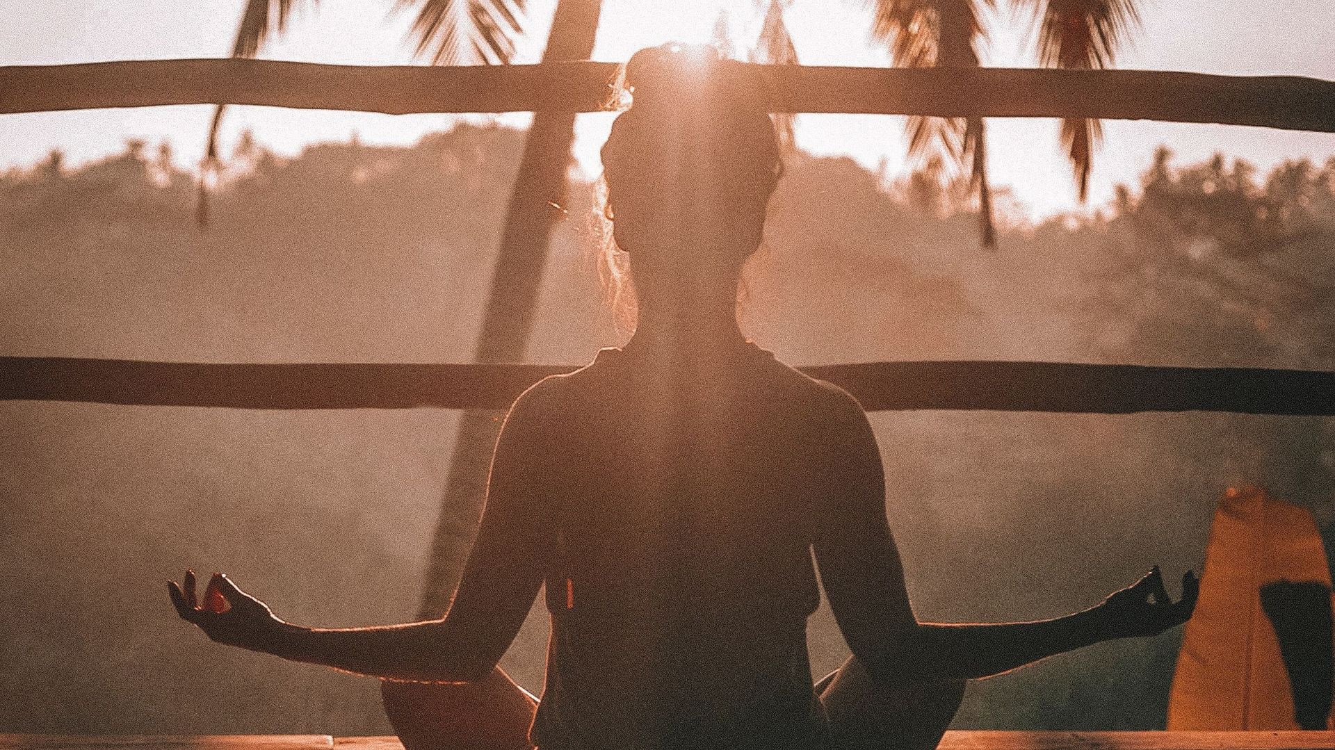A woman is sitting in a lotus position with her eyes closed.