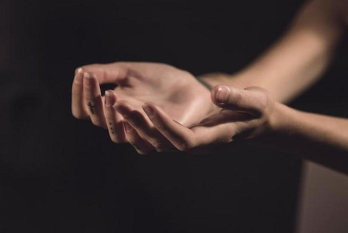 A woman is holding something in her hands in a dark room.