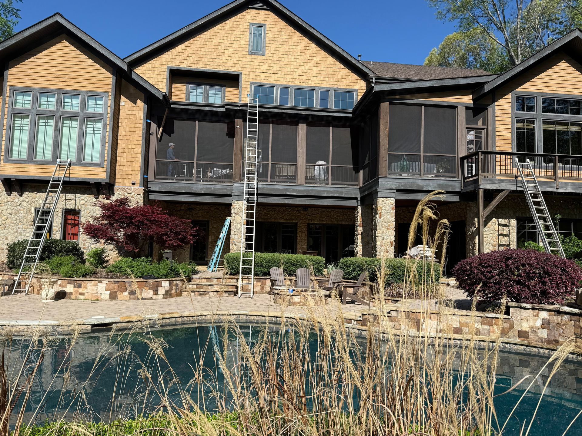 Large house exterior with pool; ladders propped against the building for construction work.