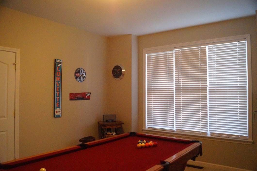 A red pool table in a room with a window and sports memorabilia.