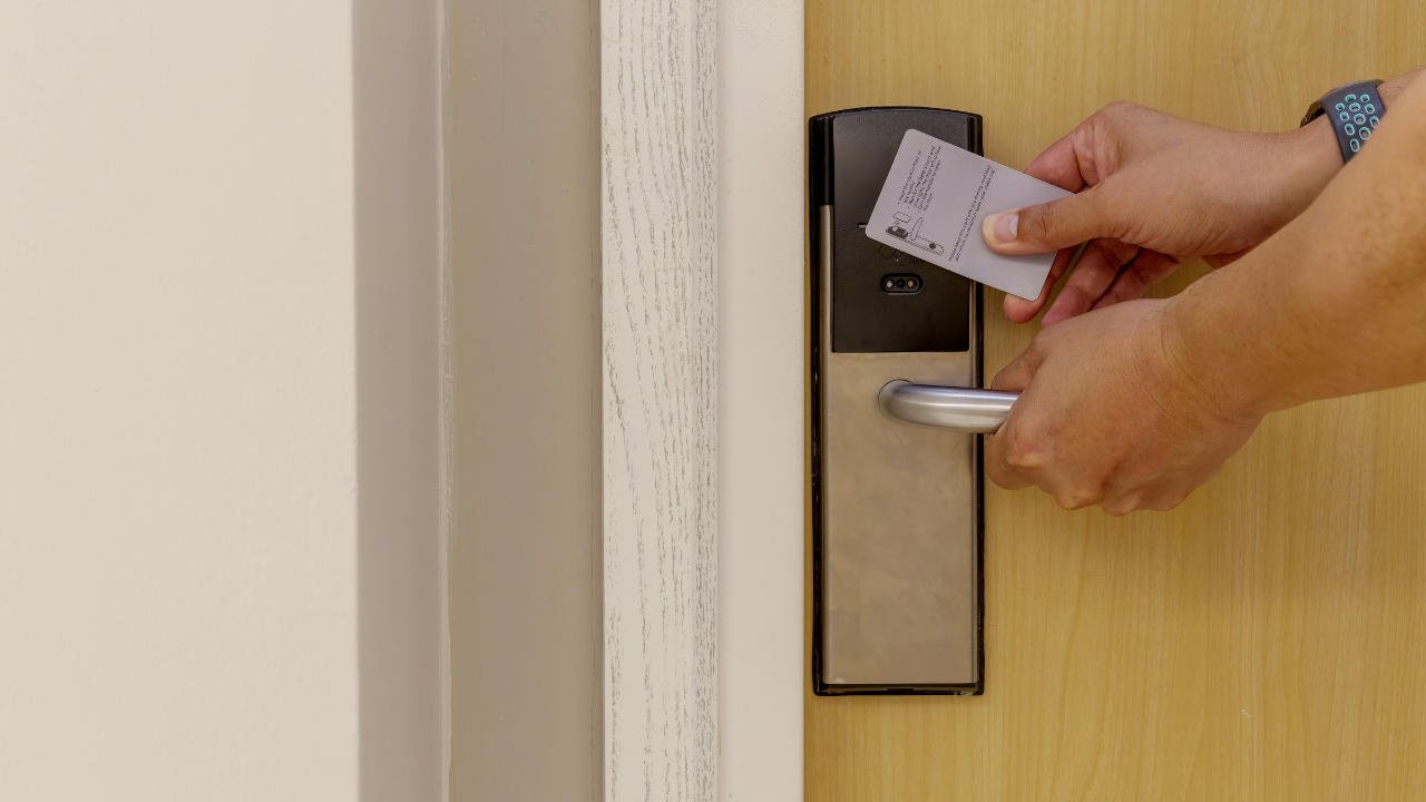Hands using a keycard to open a beige door lock