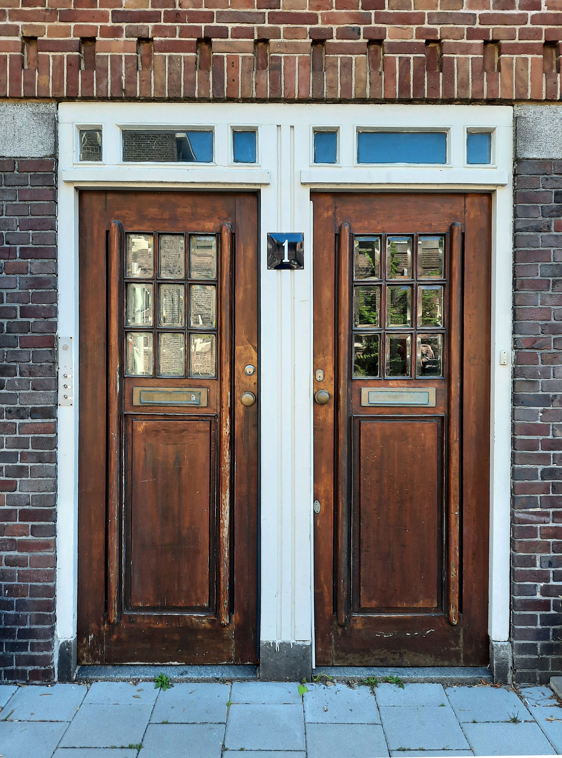 Person installing a metal hinge on a wooden door frame with a screwdriver