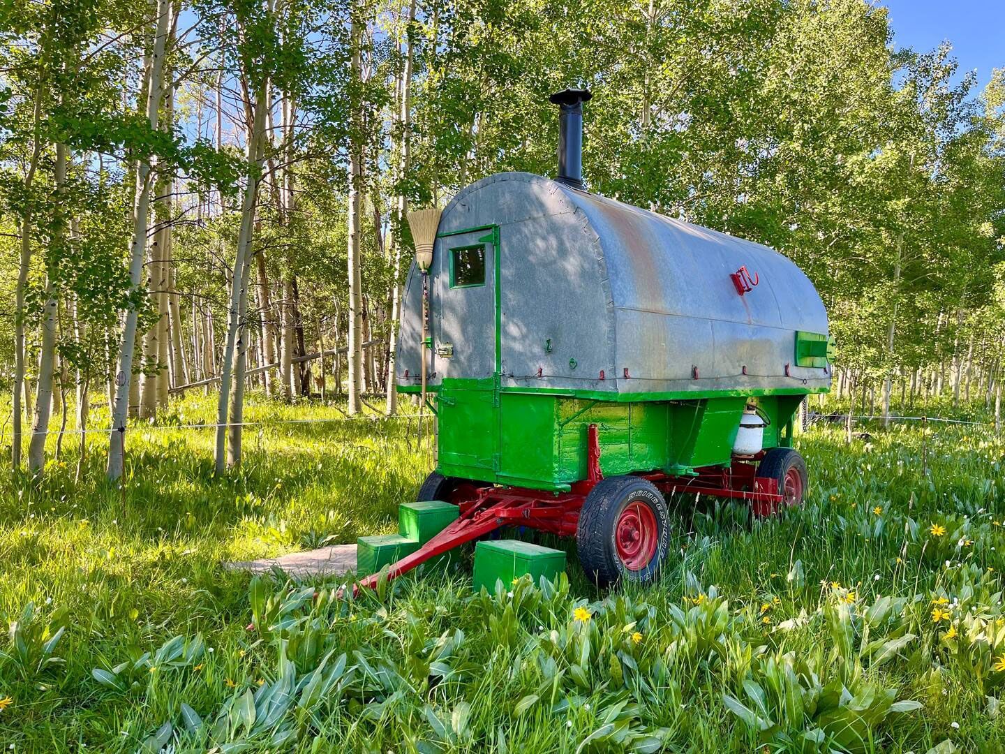 A green and white wagon is parked in a grassy field.