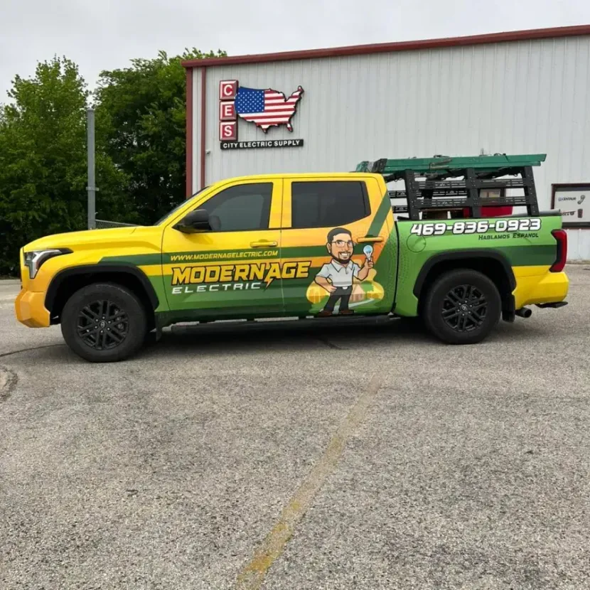 Yellow Modern Age Roofing pickup truck parked outside a building, with ladders in the bed.