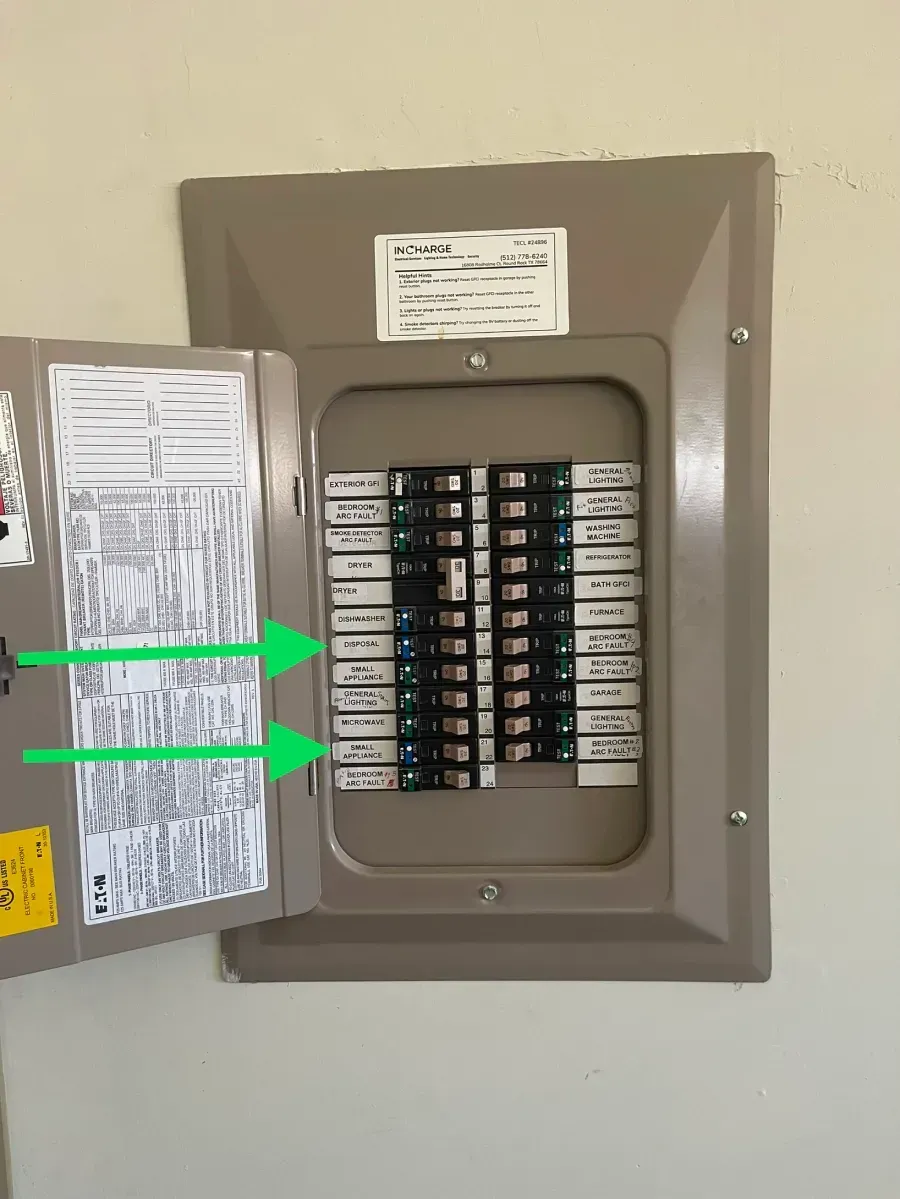 Open circuit breaker panel with two green arrows pointing to switches on the left side.