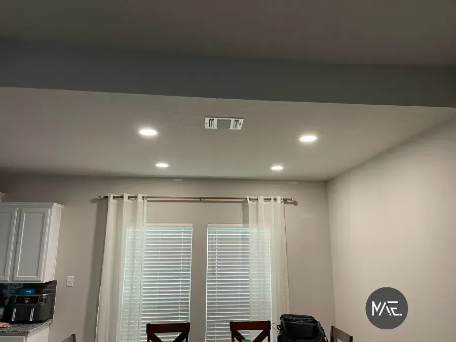 Kitchen with recessed lights, white cabinet, window blinds, and a round wall sign on a gray wall