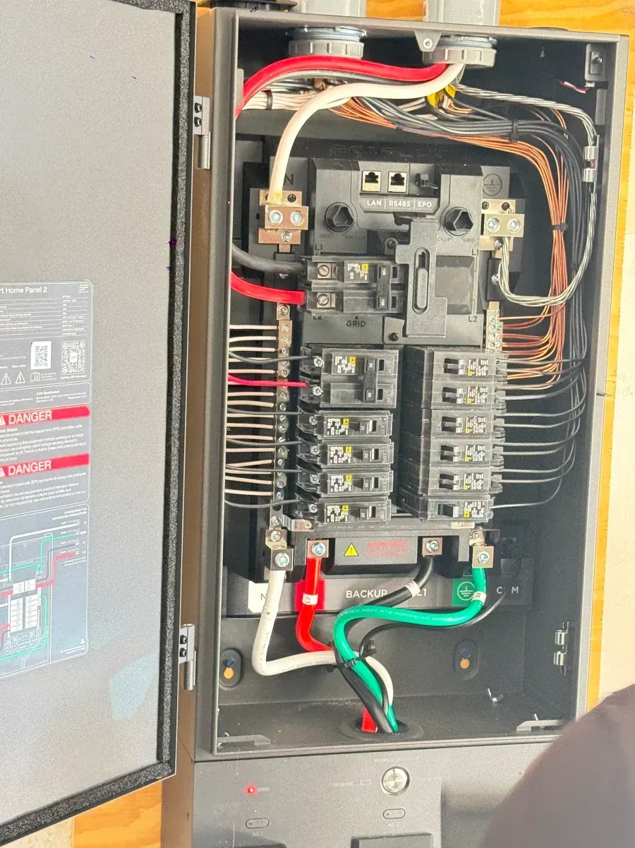 Open electrical breaker panel with exposed wiring and circuit breakers in a metal cabinet